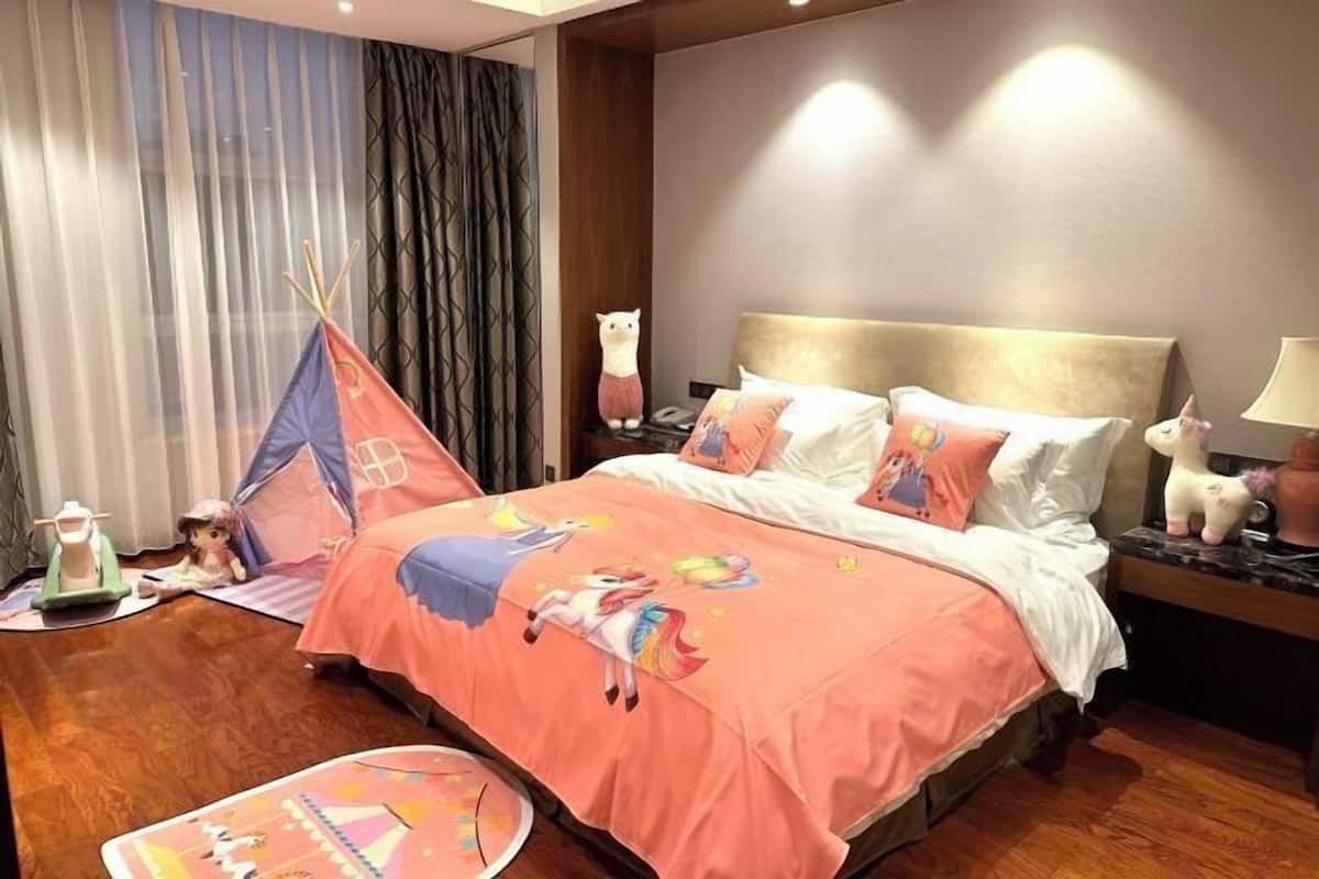 Een hotelkamer met een groot bed, nachtkastje, lamp, teddybeer en een tent.
