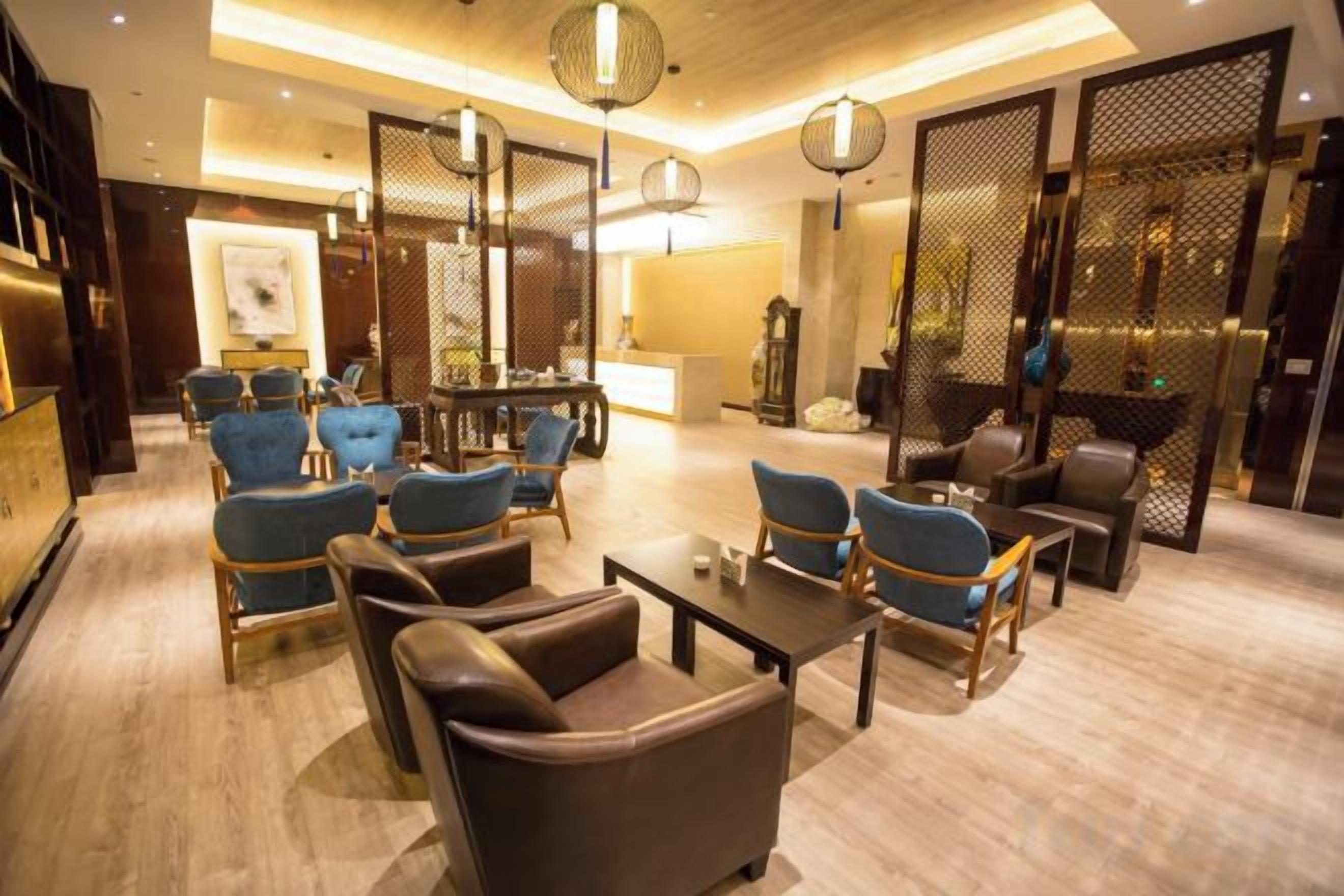 A hotel lobby with a seating area, a reception desk, and a decorative screen.