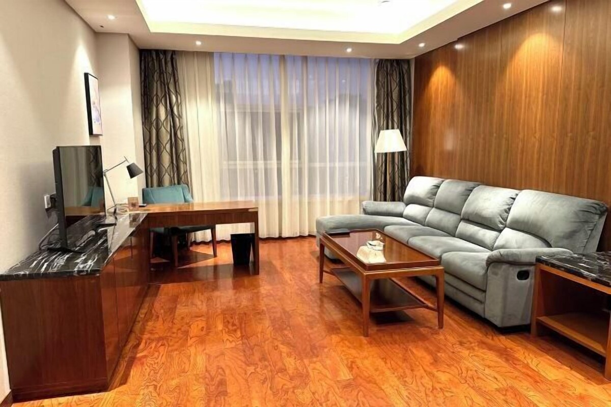 Una sala moderna con sofá, una mesa de centro, un televisor y un escritorio de madera.