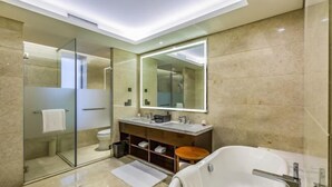 A modern bathroom with a glass-enclosed shower, a large mirror, a vanity with a sink, and a freestanding bathtub.