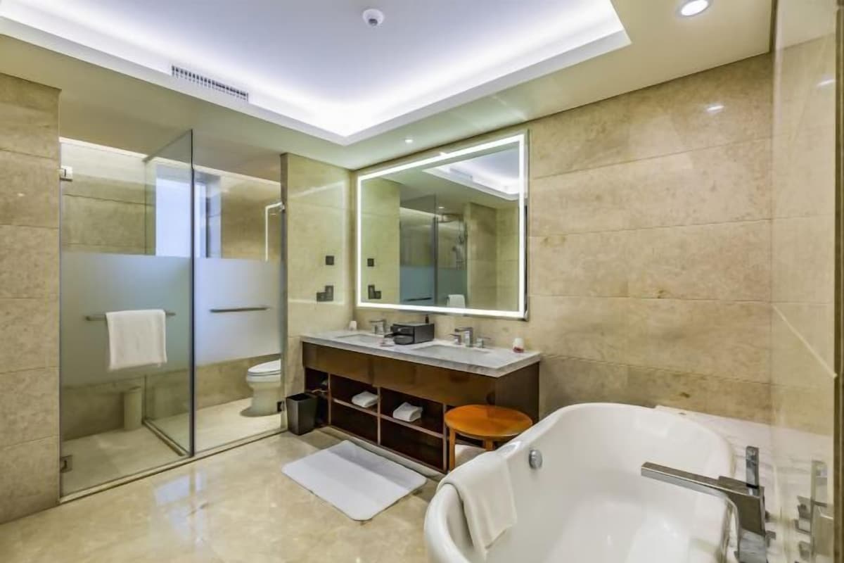 A modern bathroom with a glass-enclosed shower, a large mirror, a vanity with a sink, and a freestanding bathtub.