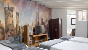 A hotel room with a cityscape mural on the wall, a wooden TV stand, a dark wardrobe, and two beds with grey bedding. - Luxury Air Road (Medellín)