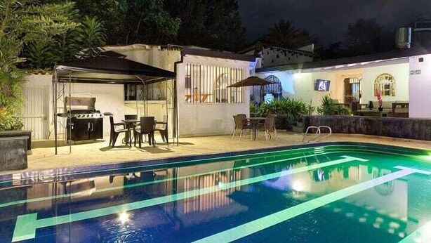 A swimming pool with a patio area, outdoor seating, and a barbecue setup. - Luxury Air Road (Medellín)