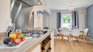 Eine moderne Küche mit Gasherd, Holzschränken und einem Essbereich mit Tisch und Stühlen.