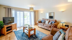 A living room with a sofa, TV, coffee table, and a large window with curtains.