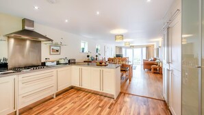 A modern kitchen with a central island, wooden flooring, and a dining area with a sofa and table.