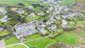 An aerial view of a coastal village with houses, roads, and a body of water.