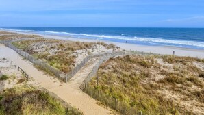 A beach with a sandy path and a wooden fence.