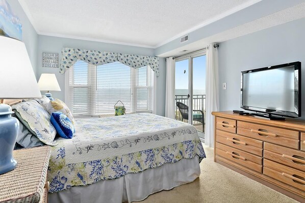 A bedroom with a bed, a dresser, a TV, and a window with blinds.