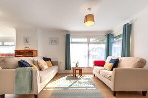 A living room with two sofas, a coffee table, and a hanging light fixture.