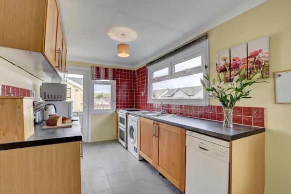 A compact kitchen with a washing machine, a dishwasher, and a microwave.