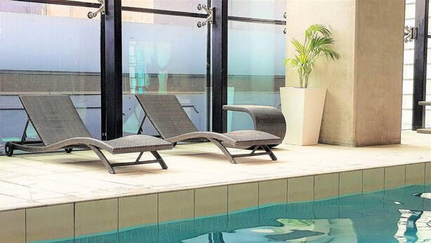 A swimming pool with two lounge chairs and a potted plant.