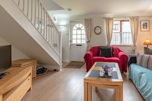 A living room with a staircase, a sofa, a coffee table, and a television.