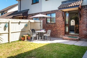 A patio with a table and chairs, a wooden fence, and potted plants.