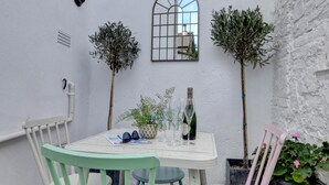 A small patio with a table and chairs, a potted plant, and a bottle of wine. - 2 Bed in Appledore (oc-whimbc) (Appledore)