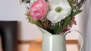 Un boccale di ceramica bianca colmo di fiori, posato su un piano di legno.