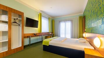 Een hotelkamer met een bed, een bureau, een televisie en een kledingkast.