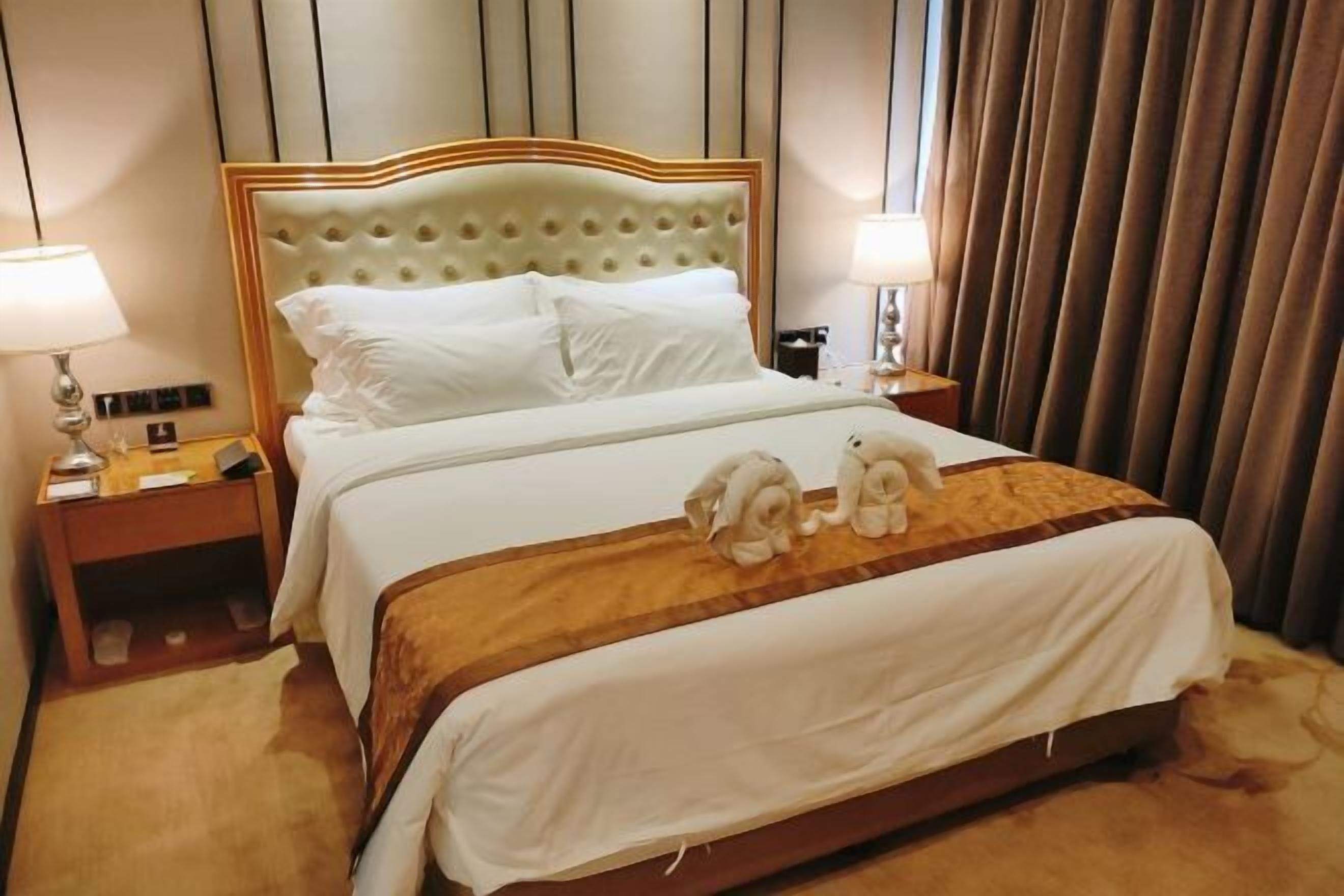 A hotel room with a large bed, two bedside tables, and a headboard.