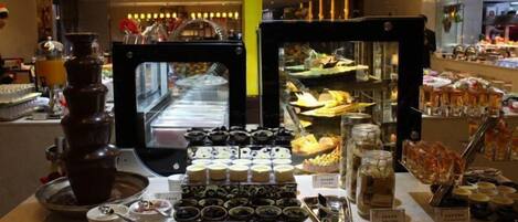 Zona de bufé con diversas opciones de comida y una fuente de chocolate.