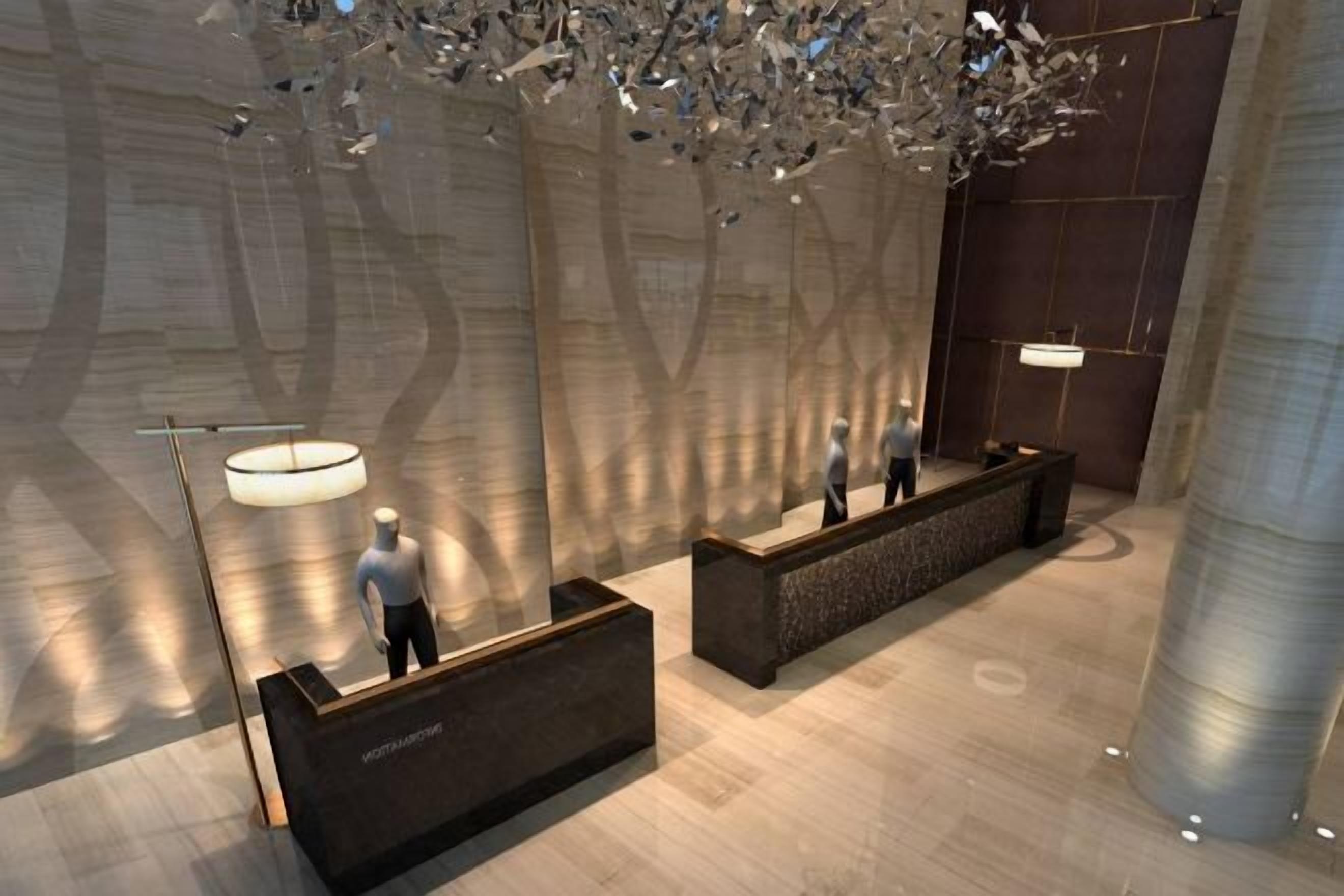 A modern reception area with a central desk, a large hanging light fixture, and a polished floor.