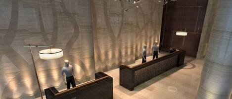 A modern reception area with a central desk, a large hanging light fixture, and a polished floor.