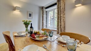 A dining table set with plates, bowls, cutlery, and a variety of food items, with a window and curtains in the background. - 2 Bed in Parracombe (oc-cottag) (Trentishoe)