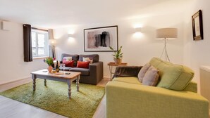 A living room with a green sofa, a grey sofa, a coffee table, a floor lamp, and a painting on the wall. - 2 Bed in Parracombe (oc-cottag) (Trentishoe)