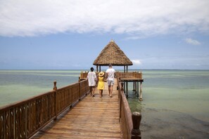A wooden pier leading to a thatched-roof structure over calm turquoise waters. - Kena Beach Villas (Marumbi)
