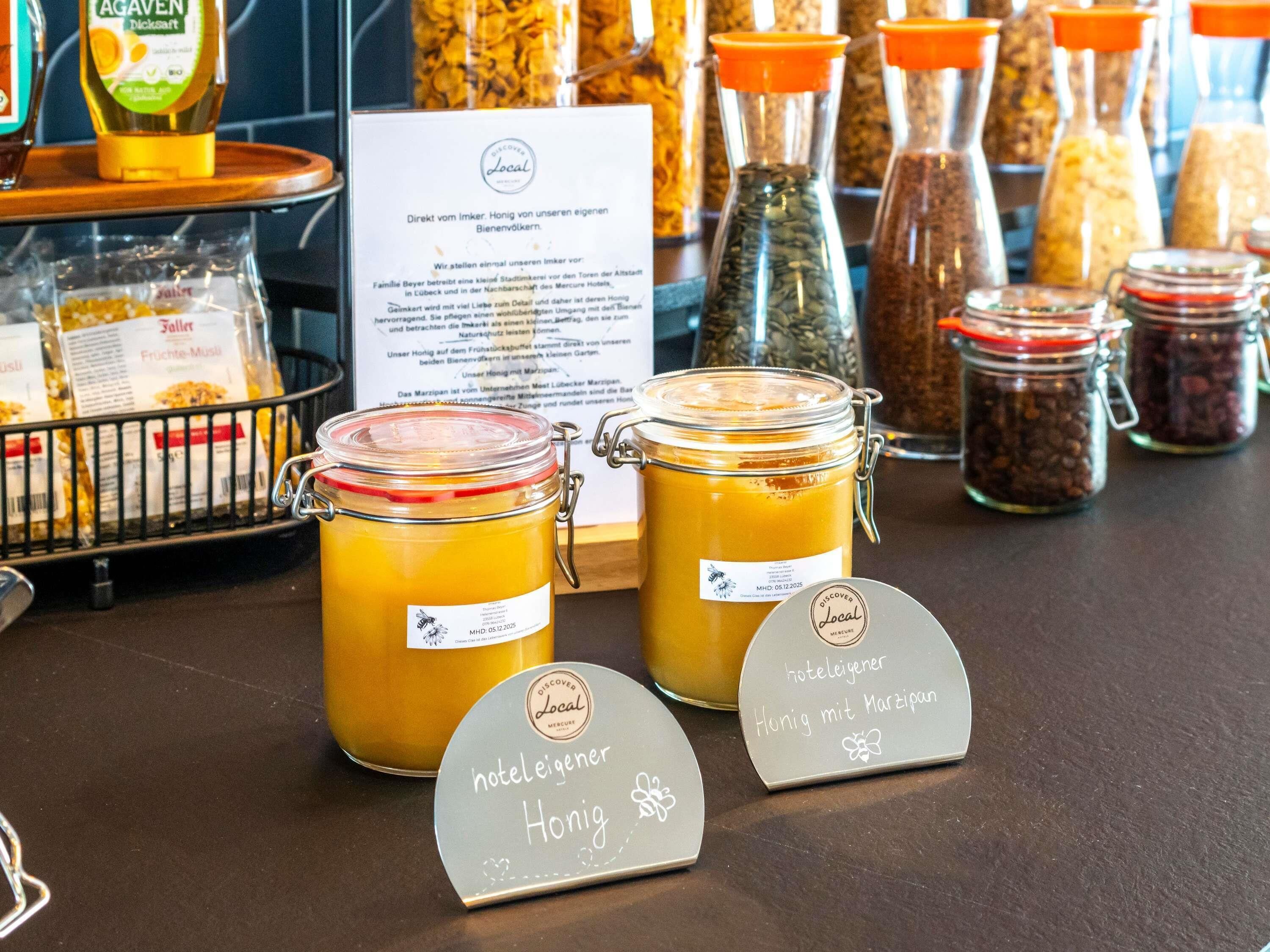 Two honey jars with labels and a sign indicating they are local honey.