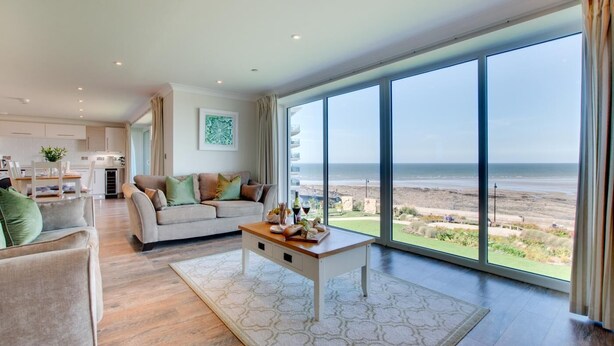 A spacious living room with a large sliding glass door leading to a beach view. - 2 Bed in Westward Ho! (oc-seaspr) (Westward Ho!)