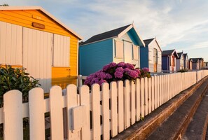 A row of colorful beach huts with a white picket fence in front. - 2 Bed in Westward Ho! (oc-seaspr) (Westward Ho!)