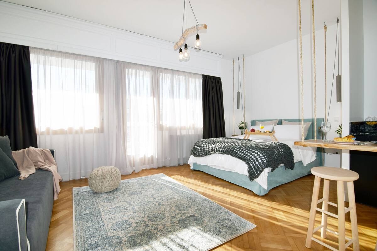 Ein modernes Schlafzimmer mit einem Bett, einem Sofa, Holzboden und einem Schreibtisch mit Stuhl.