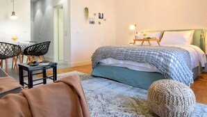 A bedroom with a bed, bedside table, and a small table with a chair. - Grey Studios (Thessaloniki)
