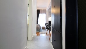 A hallway leading to a bedroom with a bed, a chair, and a desk. - Grey Studios (Thessaloniki)