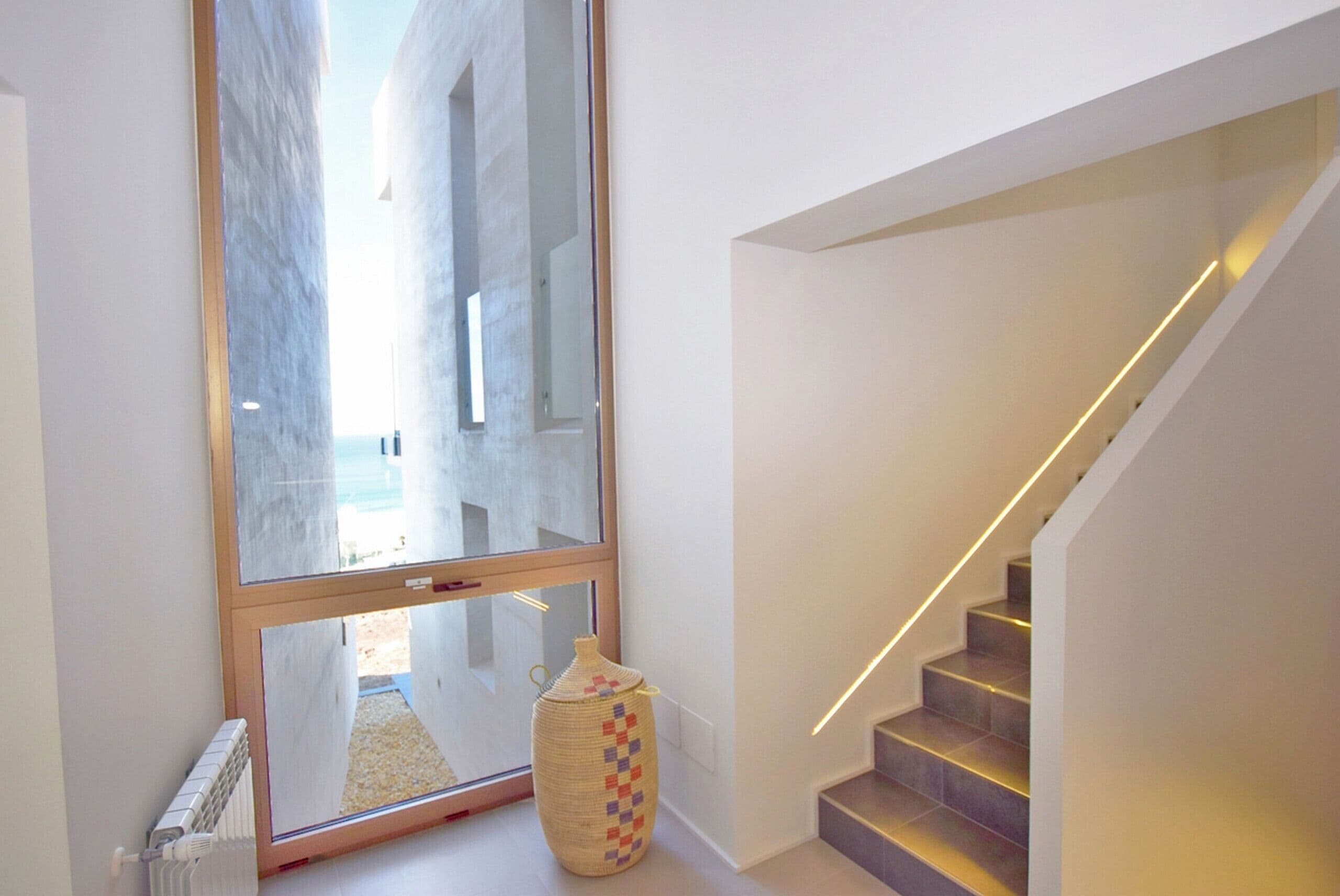 Ein modernes Interieur mit einer Treppe, einem großen Fenster und einer dekorativen Vase.