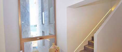 Ein modernes Interieur mit einer Treppe, einem großen Fenster und einer dekorativen Vase.