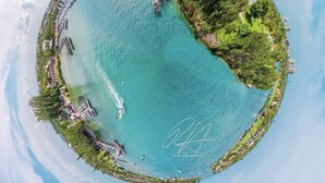 An aerial view of a coastal area with a lighthouse, pier, and residential buildings. - BEACHY BUNGALOW. Within two miles of beaches/boat ramps. Book your WINTER stay! (Jupiter)