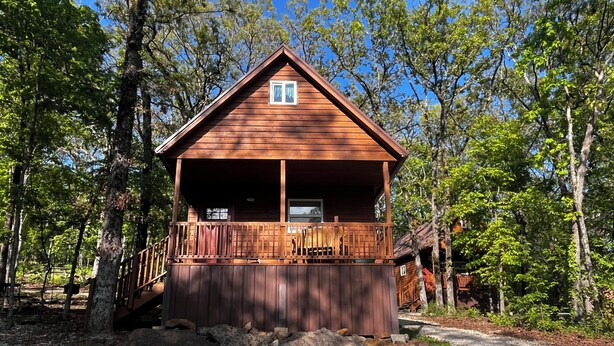 A wooden cabin with a balcony, surrounded by trees. - Grandma's cabin nestled in a little woodland village – playground, pond and more (Winslow)