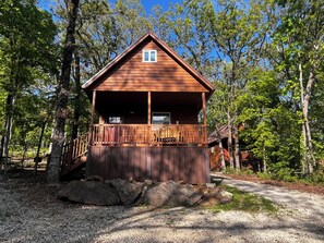 A wooden cabin with a balcony, surrounded by trees. - Grandma's cabin nestled in a little woodland village – playground, pond and more (Winslow)
