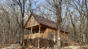 A log cabin with a balcony, surrounded by a forest. - Grandma's cabin nestled in a little woodland village – playground, pond and more (Winslow)