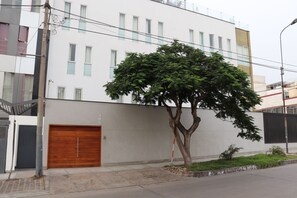 Un edificio moderno con una puerta grande de madera, un árbol en frente y un cielo despejado.