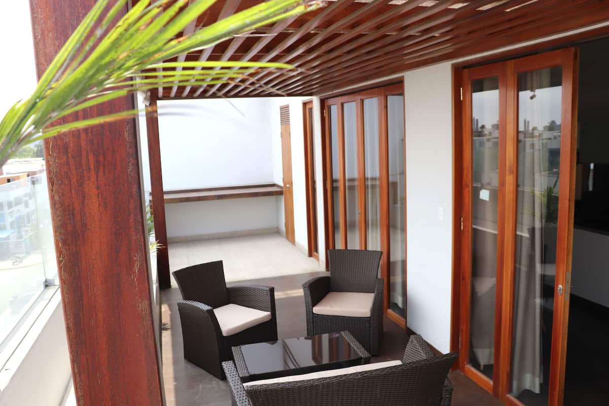 A balcony with wicker furniture and a glass door.