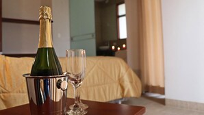 A bottle of champagne in a metal bucket and a glass on a wooden table in a hotel room. - Residencial Cafferata (Lima)