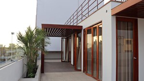 A modern building with a covered outdoor area, large windows, and a potted plant. - Residencial Cafferata (Lima)
