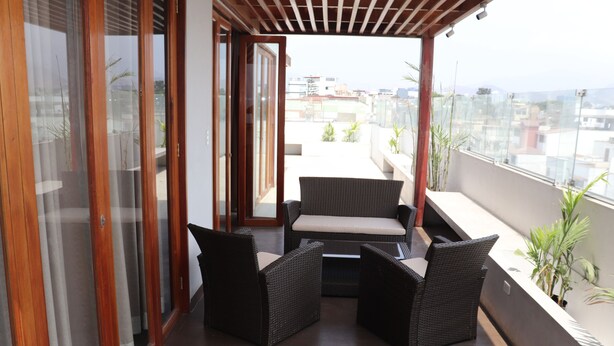A balcony with wicker furniture and a view of the cityscape. - Residencial Cafferata (Lima)