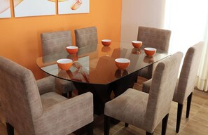 Un comedor moderno con una mesa de vidrio rodeada por seis sillas, cada una con un cuenco encima.