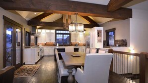 Une cuisine moderne avec des meubles blancs, une table à manger en bois et un lustre.