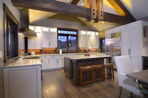 A spacious kitchen with a large island, white cabinetry, and a wooden ceiling beam.