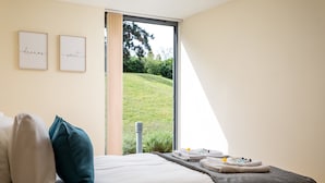 Ein Hotelzimmer mit einem Bett, Kissen, einem Nachttisch mit Handtüchern und zwei gerahmten inspirierenden Zitaten an der Wand.