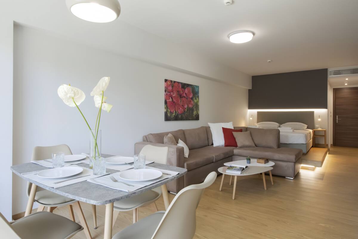 Un salon moderne comprenant un coin repas, un ensemble de canapés et un téléviseur à écran plat.